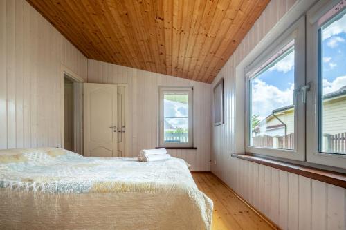 a bedroom with a bed and two windows at Nameliai pas Jolita in Palanga
