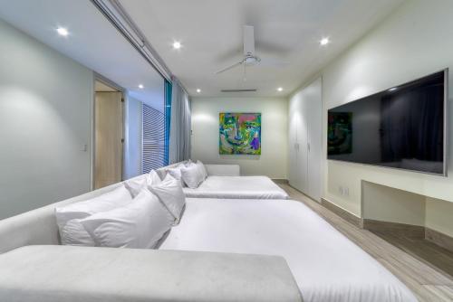 two beds in a room with a large television at Maxwell Residences at Indah in Puerto Vallarta