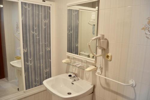 a white bathroom with a sink and a shower at Hostal La Corte in Carrión de los Condes
