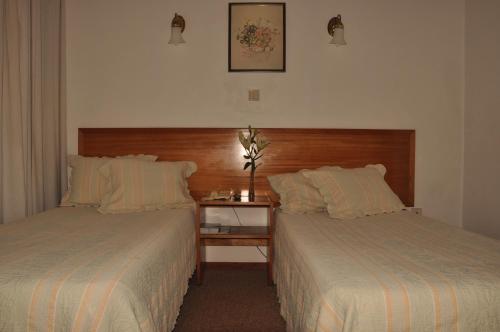 a bedroom with two beds and a table with a lamp at Residencial D. João III in Ponta Delgada
