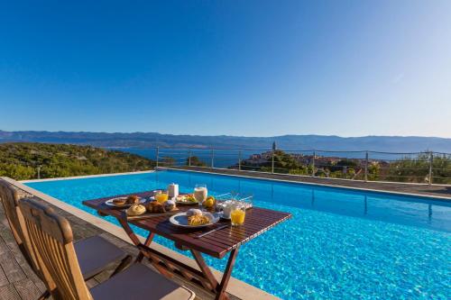 a table with food on it next to a swimming pool at Villa Vrbnik in Vrbnik