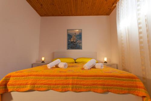 a bedroom with a bed with a yellow and orange blanket at Apartman Budimir in Cres