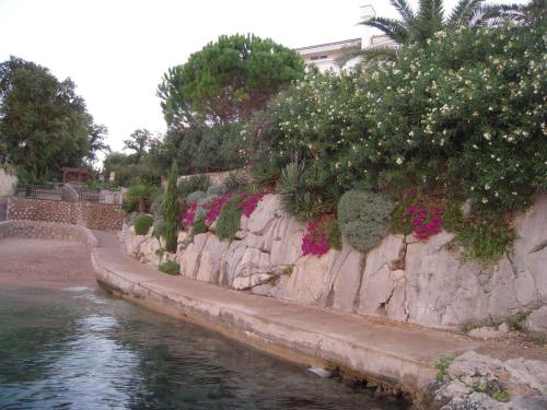 a retaining wall next to a river with flowers at Apartment in Malinska II in Malinska