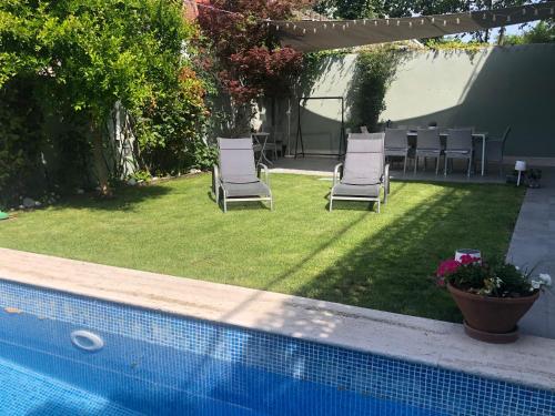 two chairs and a table and a swimming pool at chalet villa inside Madrid in Madrid