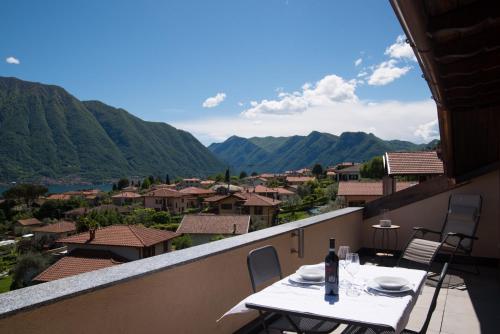 a table on a balcony with a view of the mountains at Mansarda I Cipressi in Lenno