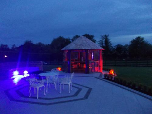 a gazebo with tables and chairs at night at Glendaloch B&B in Antrim