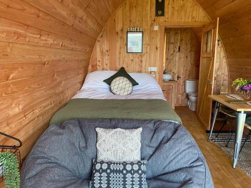 a bed in a log cabin with a table at Hendre-Aur Glamping Pod in Machynlleth