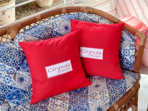 two red pillows sitting on a wicker chair at Pousada Ciranda in Itamaracá