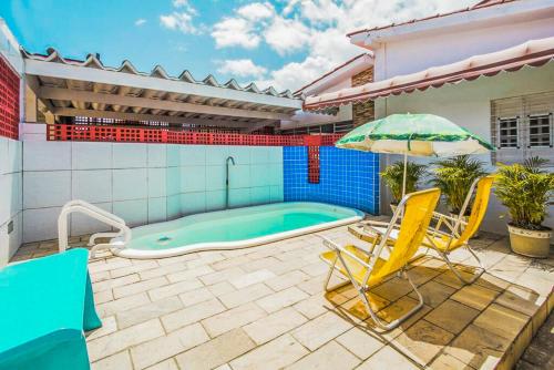 - une piscine avec 2 chaises et un parasol dans l'établissement Pousada Ciranda, à Itamaracá