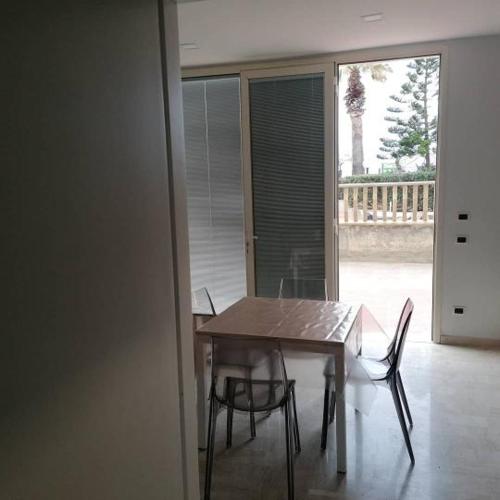 a wooden table and chairs in a room with a window at Zibibbo Beach Apartments - Trapani in Trapani