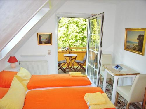 a bedroom with an orange bed and a balcony at Ostsee Hotel-Pension An der Lindenallee in Bad Doberan