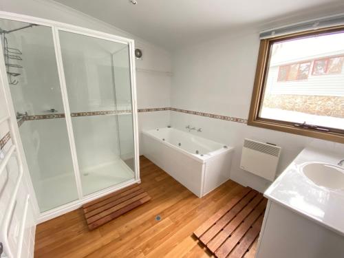 a bathroom with a tub and a shower and a sink at Verandering in Dinner Plain