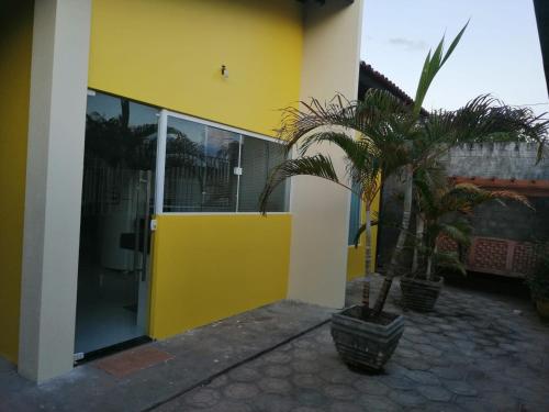 a yellow building with a palm tree in front of it at CASA TEMPORADA BARREIRINHAS 2 Quartos in Barreirinhas