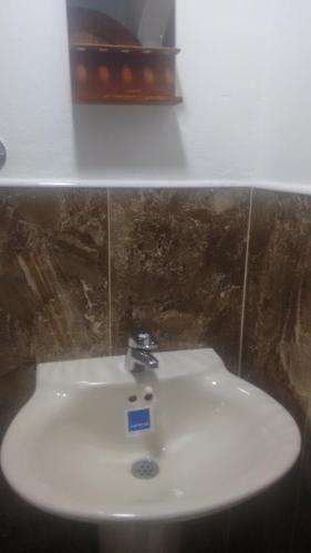 a white sink with a sign on it in a bathroom at Hostal central villa rosita in Villa de Leyva