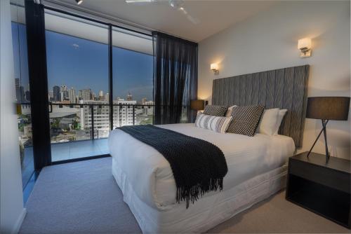 a bedroom with a large bed and a large window at Arena Apartments by CLLIX in Brisbane