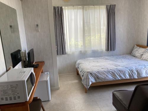 niewielka sypialnia z łóżkiem i telewizorem w obiekcie Casa di Bravo w mieście Miyako-jima