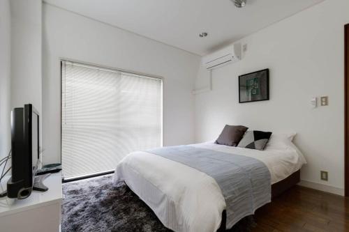 a white bedroom with a bed and a television at KB1*Unique HUGE house for family /JR +subway in Osaka