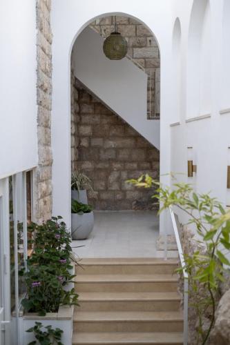 an archway with stairs in a building with plants at Khan Ein Karem Boutique Hotel in Jerusalem
