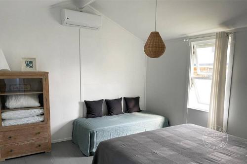 a bedroom with two beds and a cabinet and a window at Breezy Blue on Bribie in Bongaree