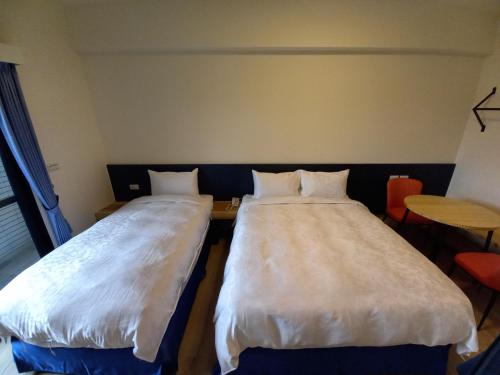 two beds sitting next to each other in a room at 航空棧輕旅民宿 in Huxi
