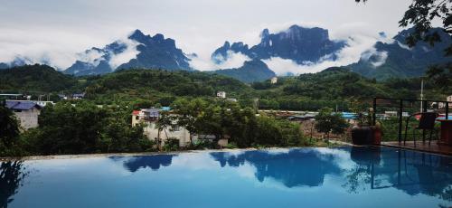 a large swimming pool with mountains in the background at Tujia folk houses in Zhangjiajie