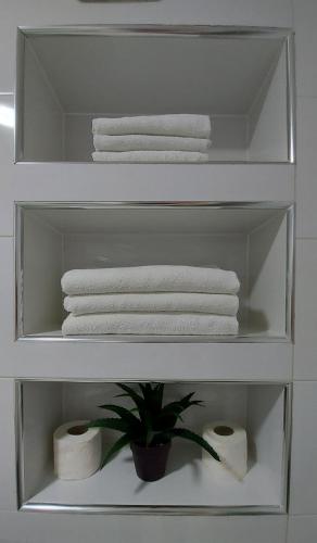 a white shelf with towels and a plant in a bathroom at Apartments Kapetanovina in Mostar