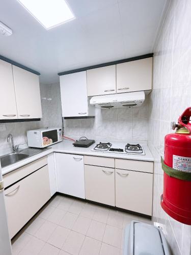 a kitchen with white cabinets and a stove top oven at Hotel Nikko Apartment Dalian in Dalian