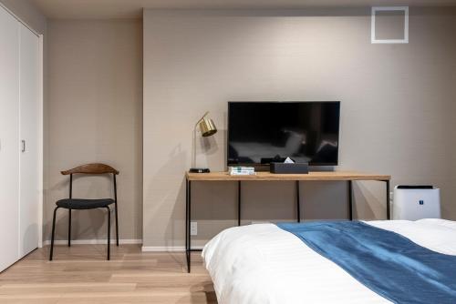 a bedroom with a bed and a desk with a television at hotel aima in Tokyo