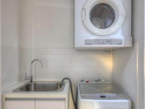 a kitchen with a sink and a washing machine at Maggies Beachfront Apartment 4 in Horseshoe Bay