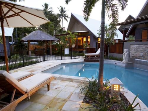 a swimming pool with a bench and an umbrella at Pure Magnetic Villa 4 in Nelly Bay