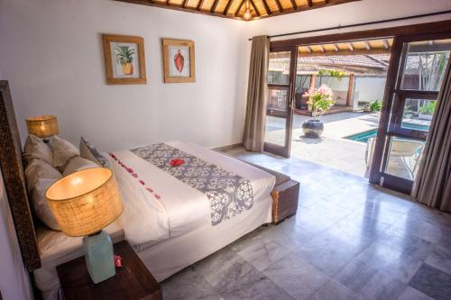 1 dormitorio con 1 cama y puerta que da a un patio en Gili Villas en Gili Trawangan