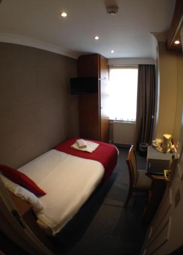 a hotel room with a bed and a window at Columbus Hotel in London