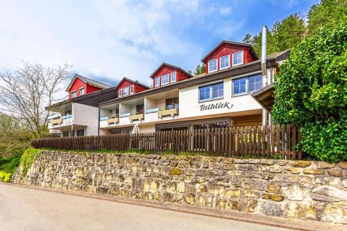 a house with a stone wall and a fence at Pension Talblick in Sulz am Neckar