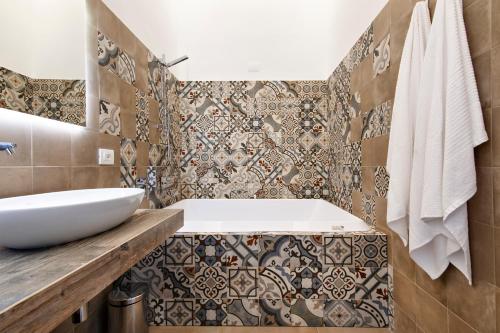 y baño con lavabo, bañera y azulejos. en Palazzo San Lazzaro - Jacuzzi Rooms & Suites SIT, en Lecce