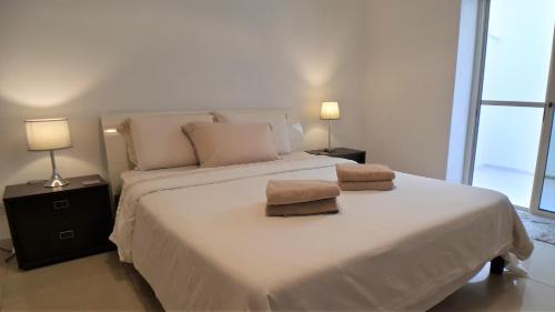 a bedroom with a large white bed with two lamps at luxuries, central Hostel ,sleep 2 in Il-Gżira