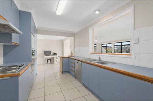 a large kitchen with a sink and a window at Harrys @ Shelly Beach - family home with pool in Port Macquarie