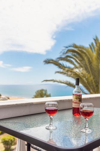 Zwei Weingläser stehen mit einer Flasche auf einem Tisch. in der Unterkunft Adriatica View in Vitalades