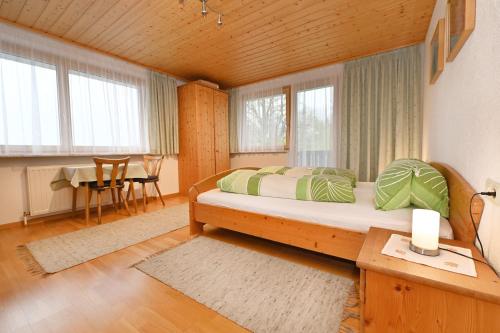 a bedroom with a bed and a table and windows at Haus Valuga in Bürserberg