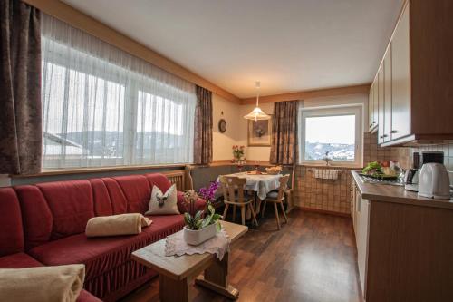 a living room with a red couch and a kitchen at Binterhof in Castelrotto