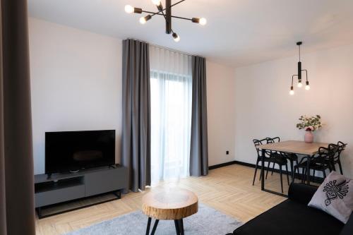 a living room with a couch and a dining room table at Stylchyn 90 Apartamenty nad Jeziorem Czorsztyńskim in Kluszkowce