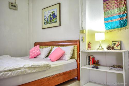 1 dormitorio con 1 cama con almohadas rosas y blancas en Serenity1 Homestay, en Chiang Dao