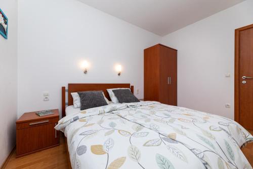 a bedroom with a large bed and a wooden cabinet at Happy Apartments Baška in Baška