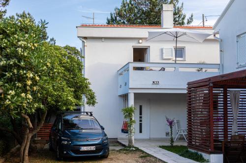 a car parked in front of a white house at Happy Apartments Baška in Baška