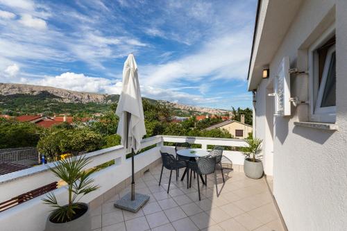 a balcony with a table and chairs and an umbrella at Happy Apartments Baška in Baška