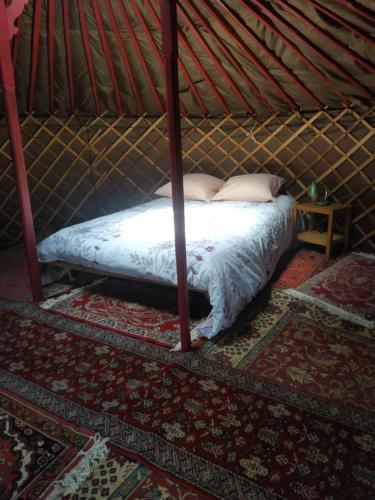Yourte rustique en permaculture في Creysse: سرير في يورت مع سيد السرير
