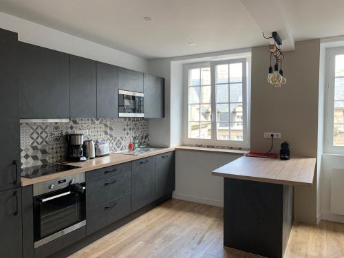 une cuisine avec des placards gris et un comptoir dans l'établissement La Suite Saint-Malo Intra-Muros T3 (2-4pers), à Saint-Malo