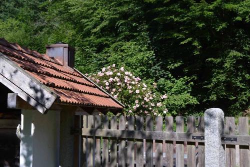 a wooden fence with pink flowers behind a wooden house at Forsthaus Heilsberg in Wiesent