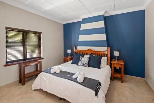 a bedroom with a large bed with blue walls at De Akker Guest House in Bloemfontein