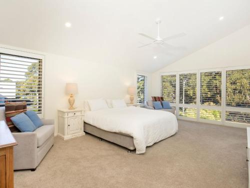 a bedroom with a bed and a couch and windows at Sapphire Sands - Pet Friendly - Community Pool in Callala Beach