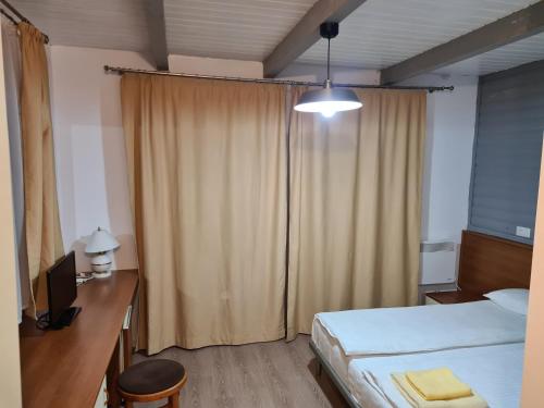 a bedroom with a bed and a desk with a television at Pensiunea Gernik 100 in Gârnic